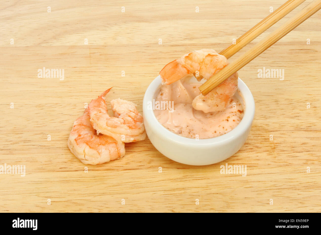 Garnele in Stäbchen eintauchen in Meeresfrüchte Sauce mit zwei Garnelen auf einem Holzbrett Stockfoto