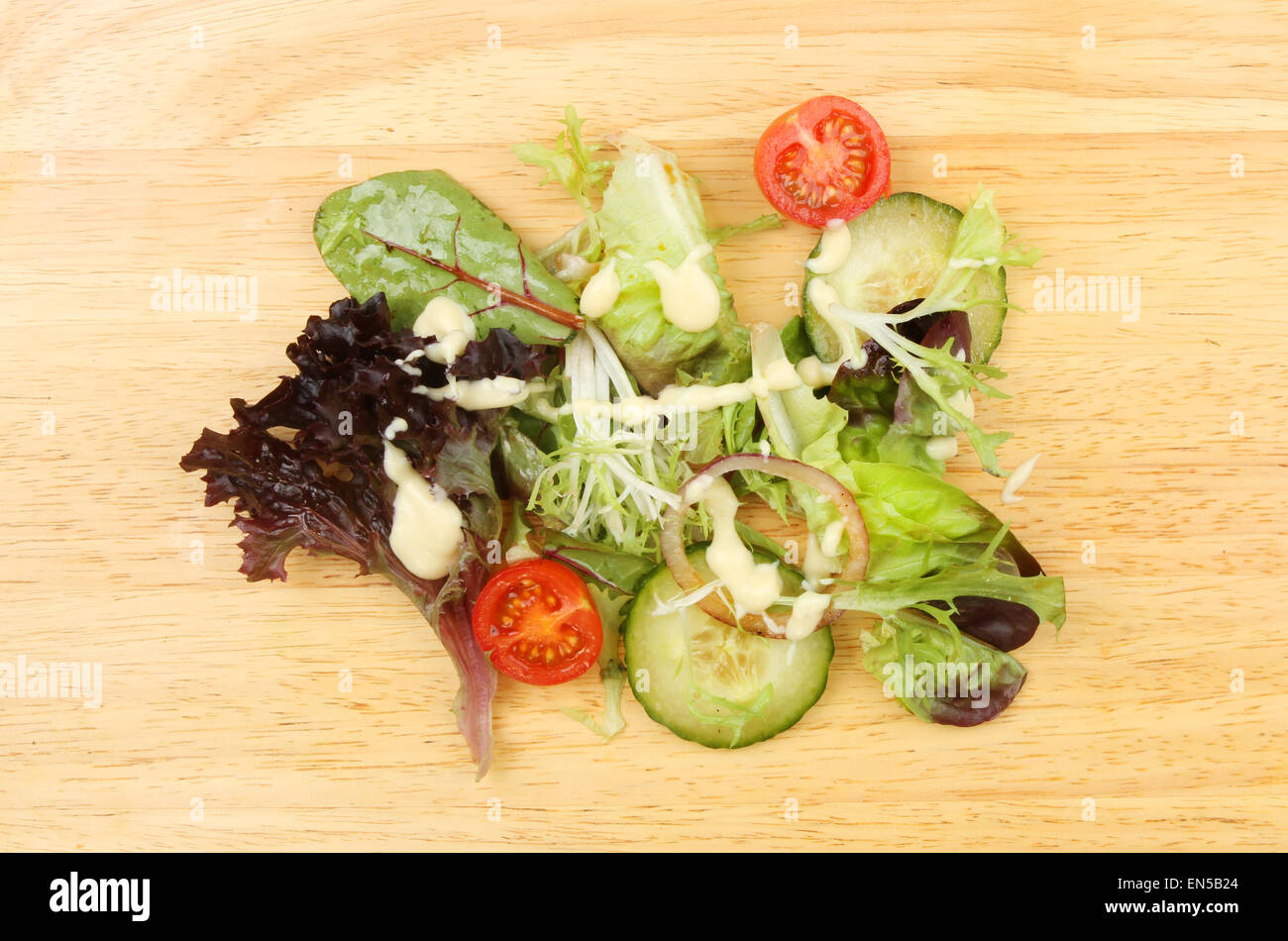 Salat mit Dressing und Salat-Creme auf einem Holzbrett Stockfoto
