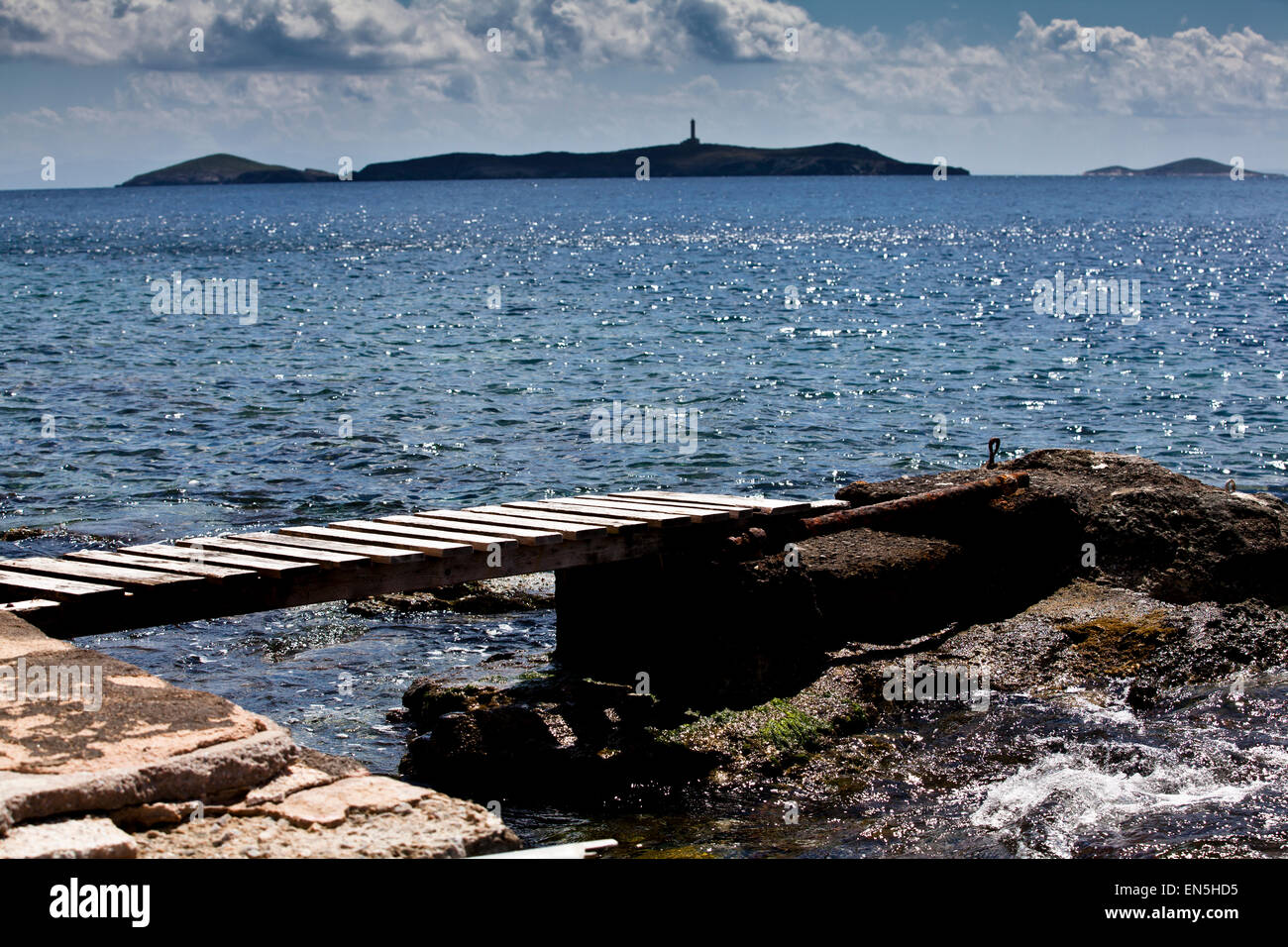 Ein Holzsteg mit der Insel Didimi im Hintergrund in der Nähe von Syros, Griechenland. Stockfoto
