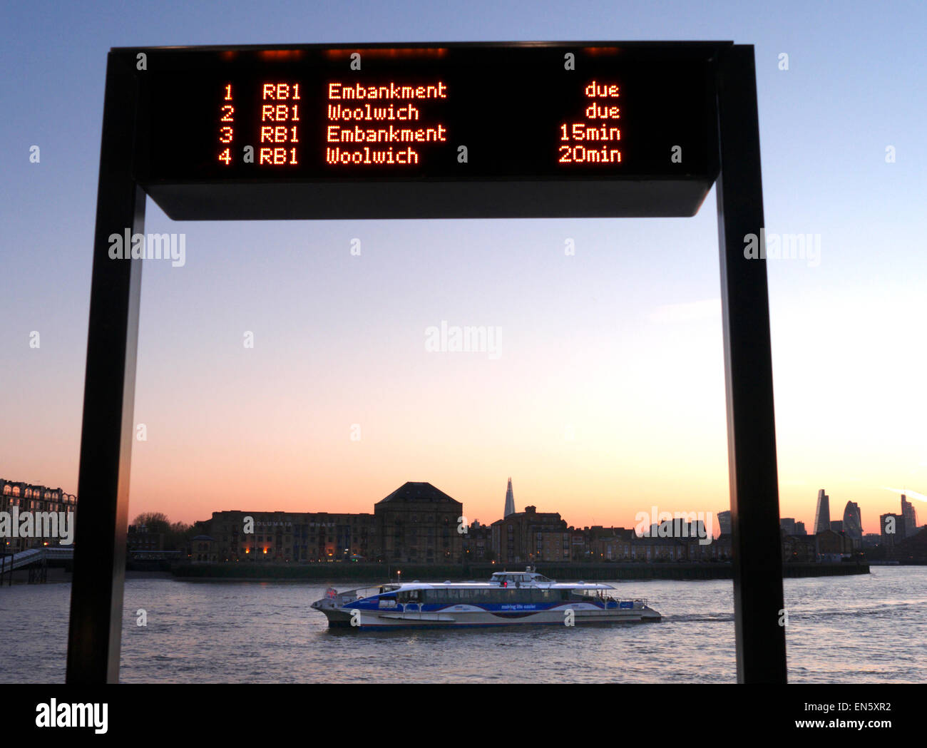 RIVER BOAT & Anreise Informationen Bildschirm und RB1 Thames Clipper Bootstour bei Sonnenuntergang am Canary Wharf anreisen, mit Shard und London City in b/g E 14. Stockfoto