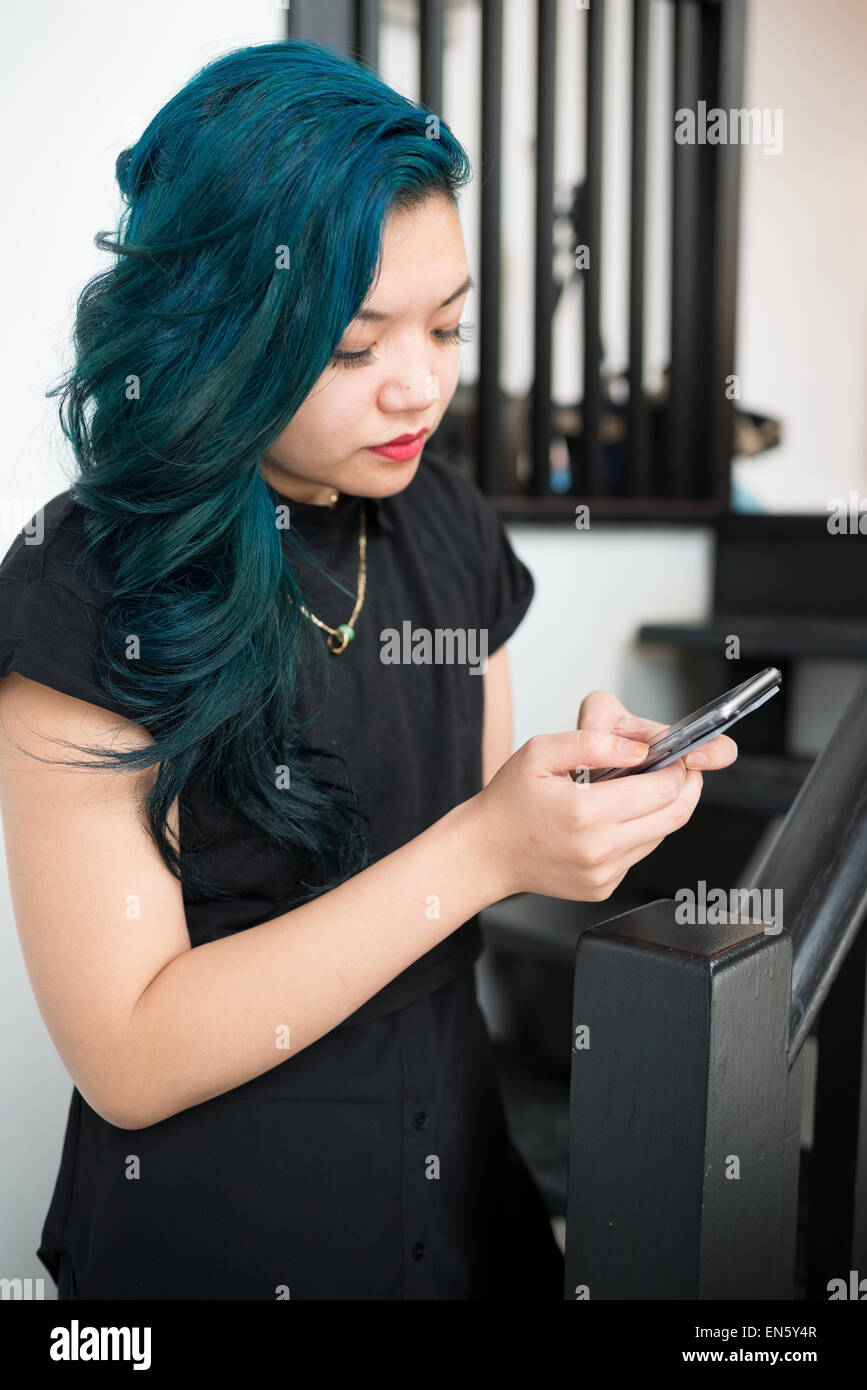 Asiatische Frau mit blauen Haaren SMS auf smartphone Stockfoto