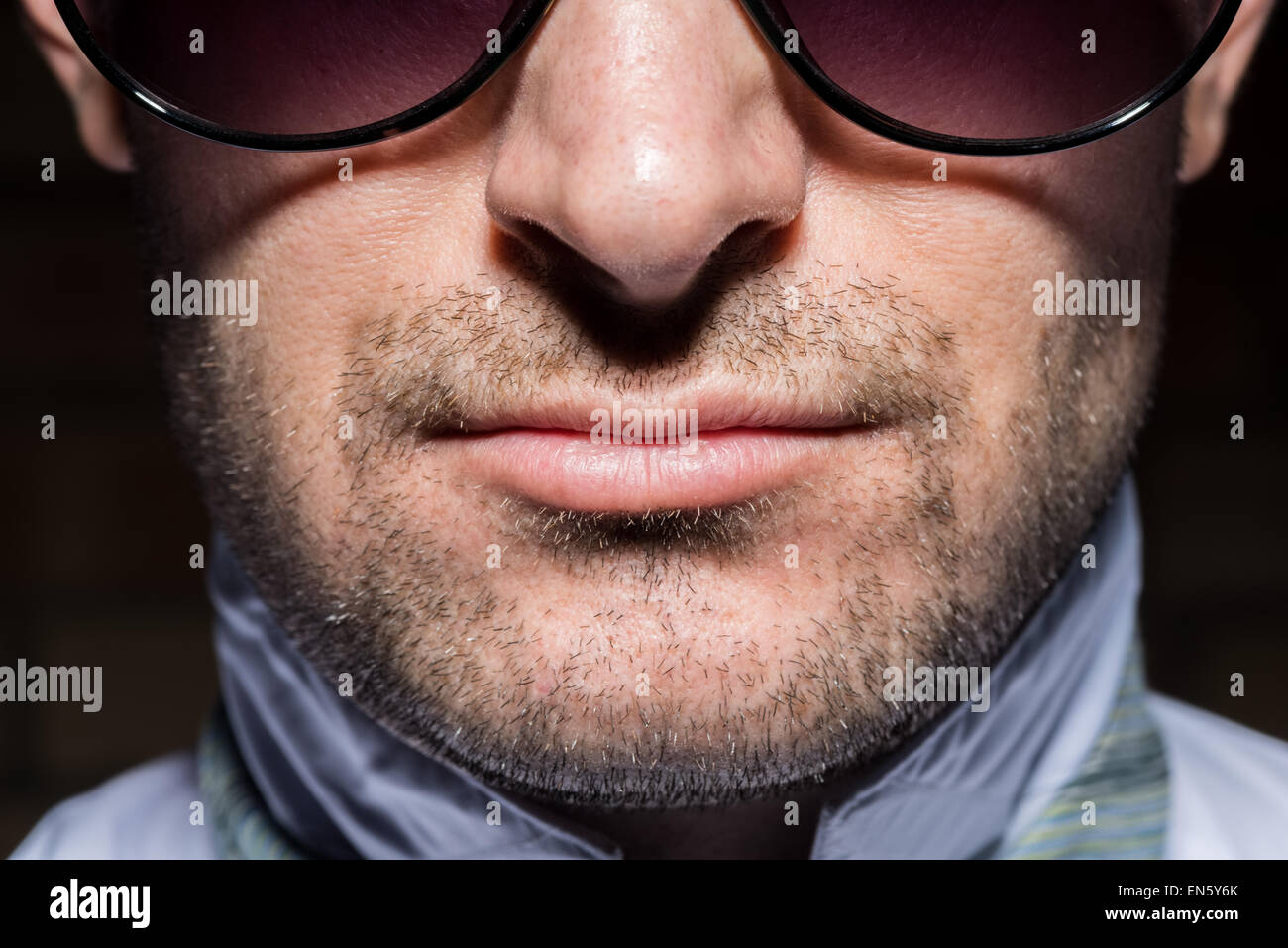 Engen Porträt eines überzeugt mit hohem Kontrast Beleuchtung mit Sonnenbrille. Mit Bartstoppeln. Stockfoto