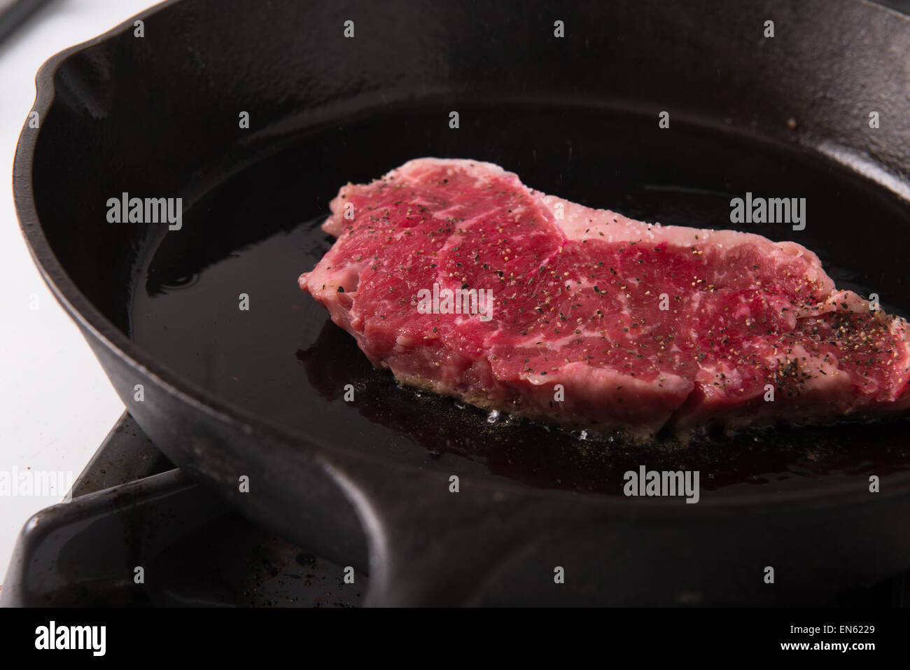 Serie: Strip Loin Steak in Gusseisen Pfanne Grillen: Steak in der Pfanne mit Salz und Pfeffer würzen, in Olivenöl Stockfoto