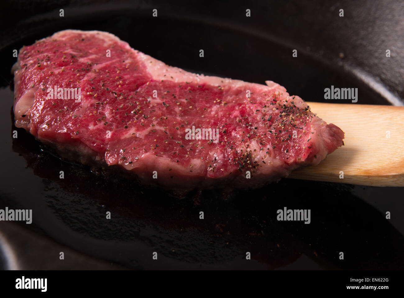 Serie: Strip Loin Steak in Gusseisen Pfanne Grillen: Steak in der Pfanne mit Salz und Pfeffer wird umgedreht Stockfoto