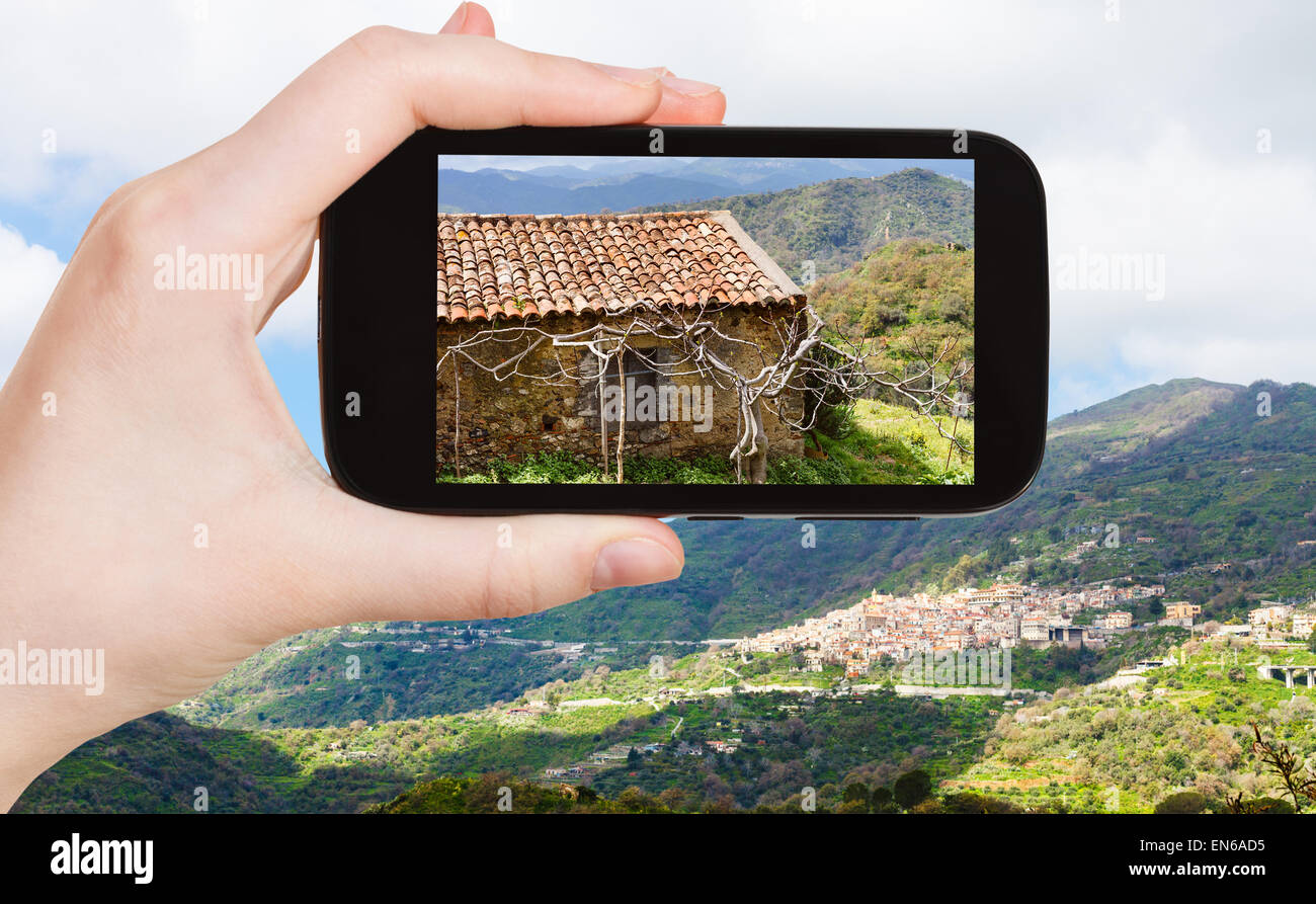 Konzept - Reisen Tourist nimmt Bild Berglandschaft mit Savoca Dorf in Sizilien im Frühjahr auf Smartphone, Italien Stockfoto