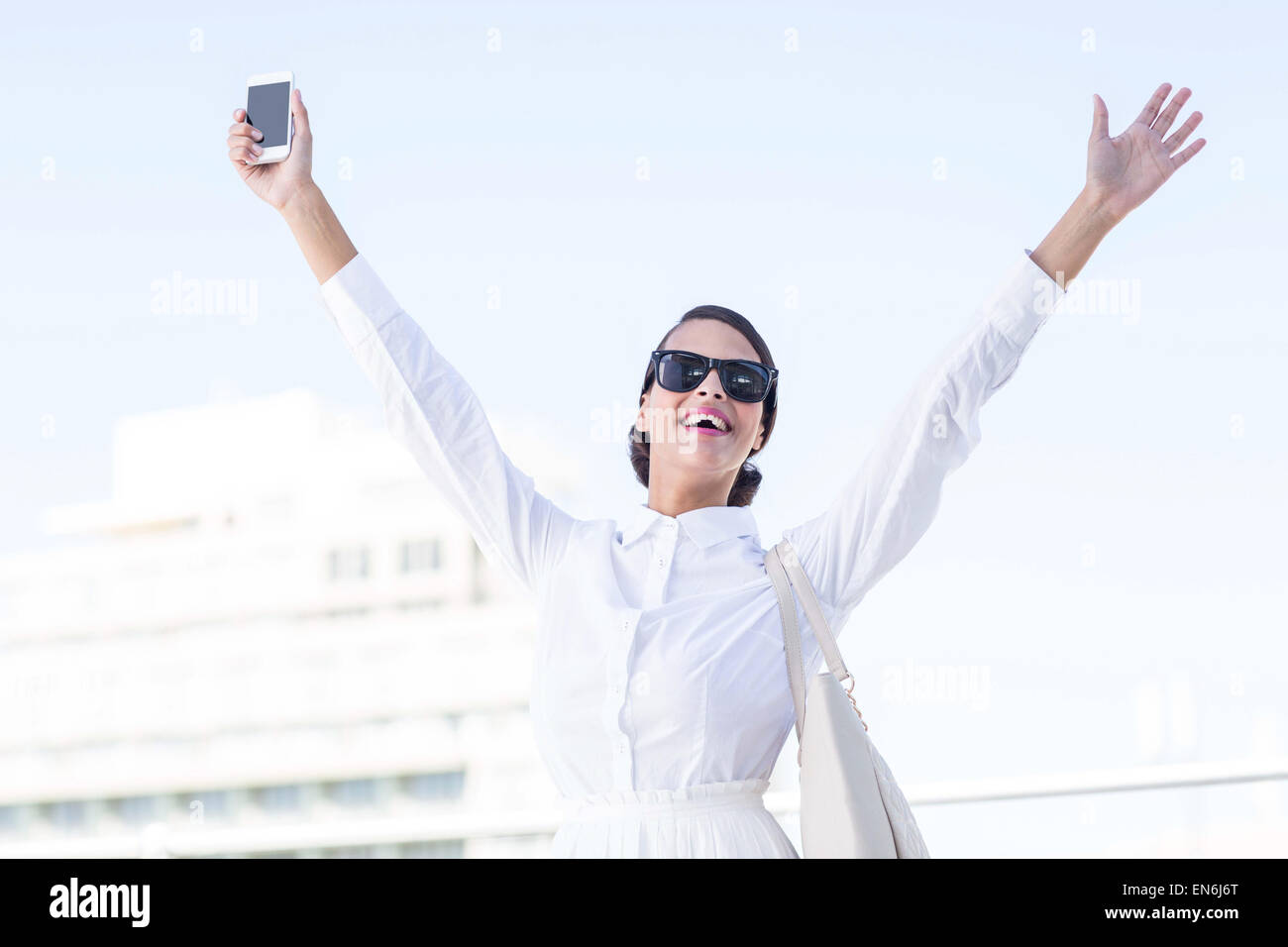 Euphorische Frau Smartphone mit Hände hochhalten Stockfoto