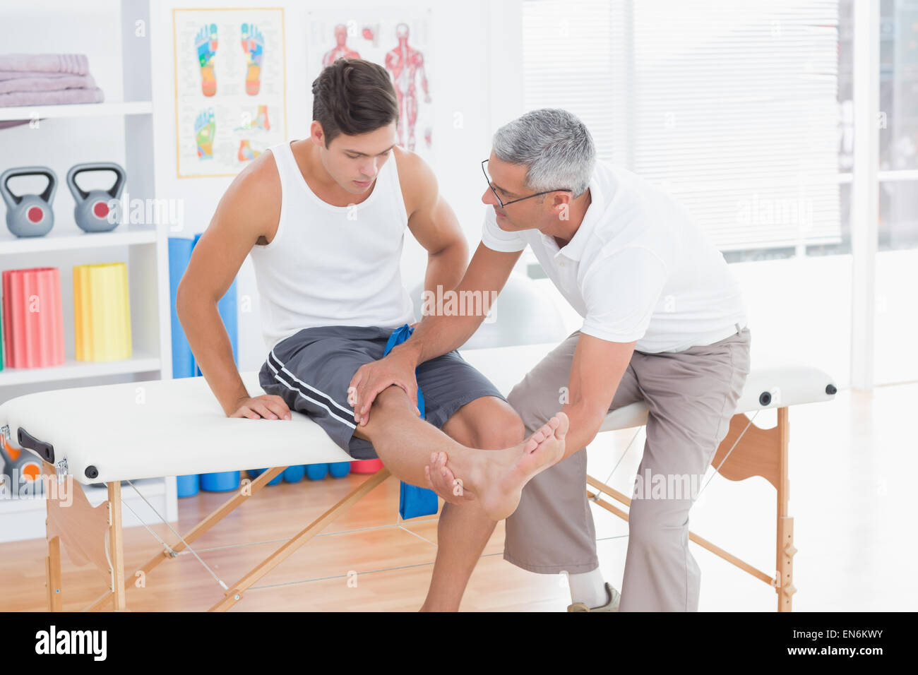 Arzt untersucht seinen Patienten Knien Stockfoto