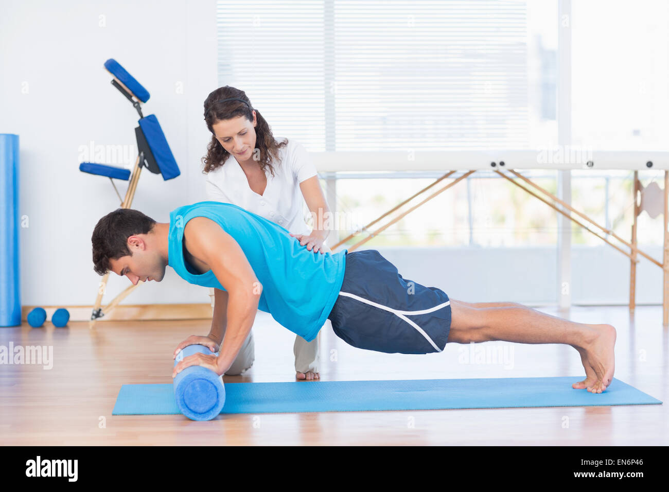 Trainer arbeiten mit Mann auf Gymnastikmatte Stockfoto