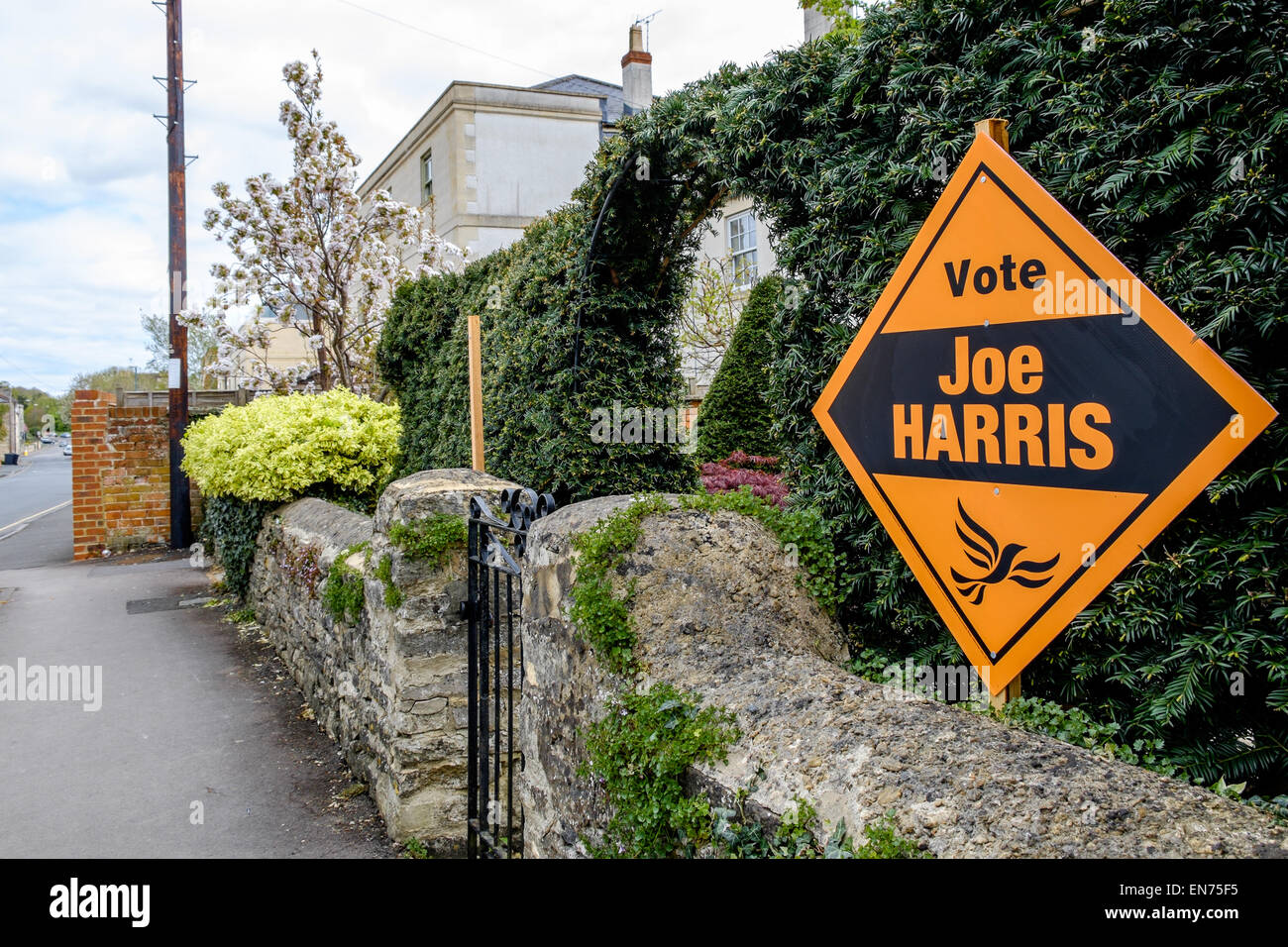 Ein Liberaldemokrat Banner fordert die Öffentlichkeit für die lokalen Kandidaten in Cirencester, Großbritannien, auf der Gartenmauer eines Hauses stimmen Stockfoto