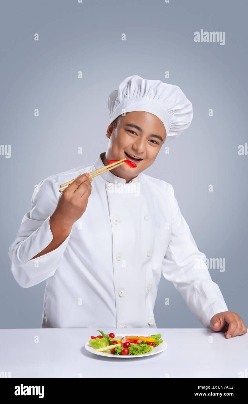 Porträt von Küchenchef Paprika mit Stäbchen zu essen Stockfoto