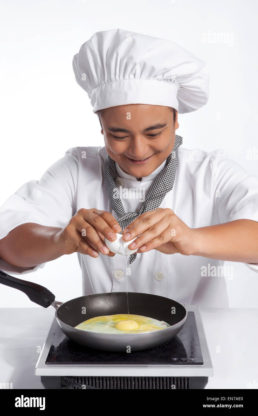 Küchenchef knacken Ei in Pfanne Stockfoto