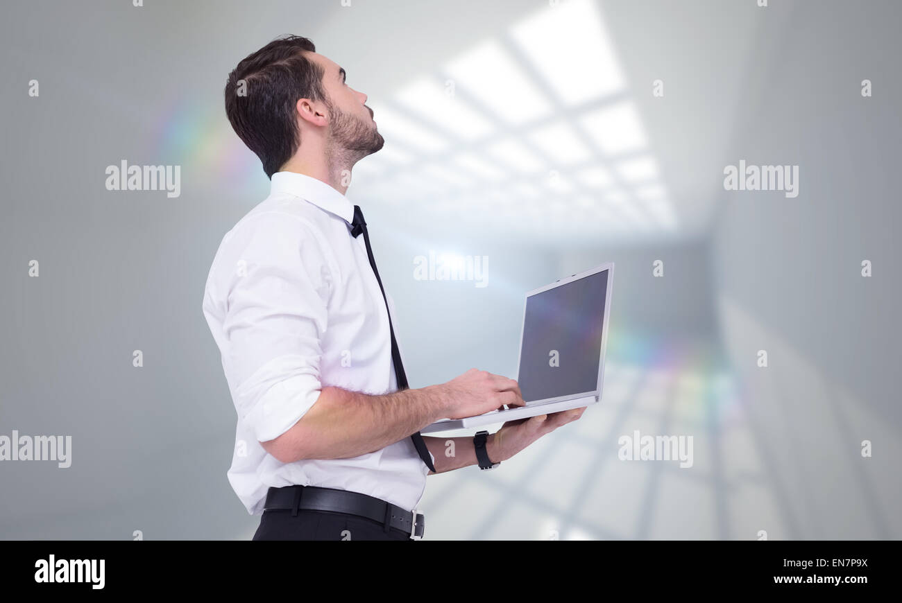 Zusammengesetztes Bild von anspruchsvollen Geschäftsmann stehend mit einem Laptop Stockfoto