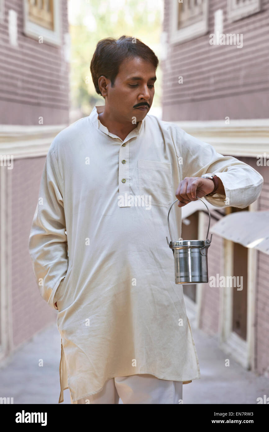 Mann hält Milch Kanister und Blick auf Uhr Stockfoto