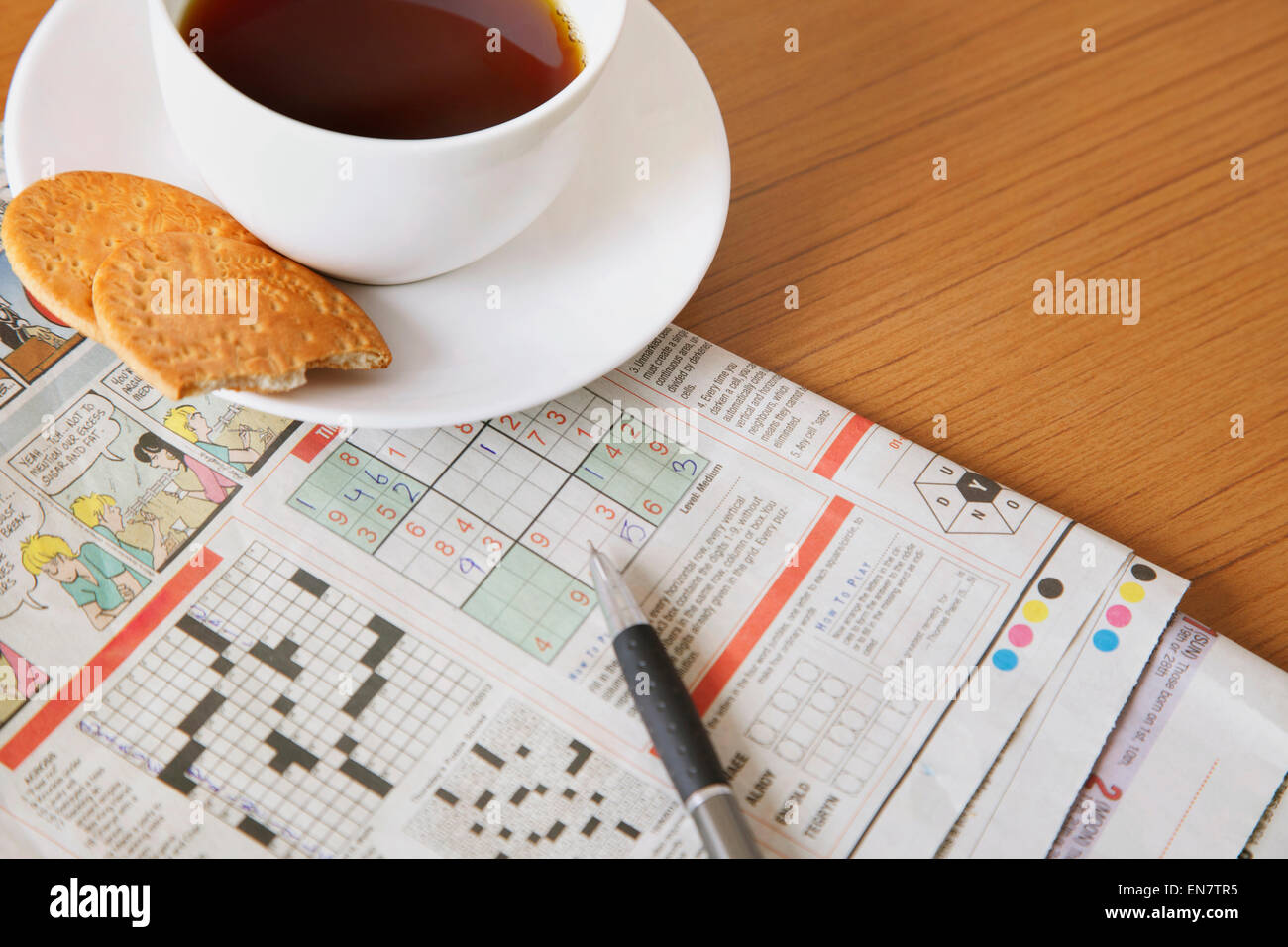 Kaffee und Gebäck mit Zeitung Kreuzworträtsel Stockfoto