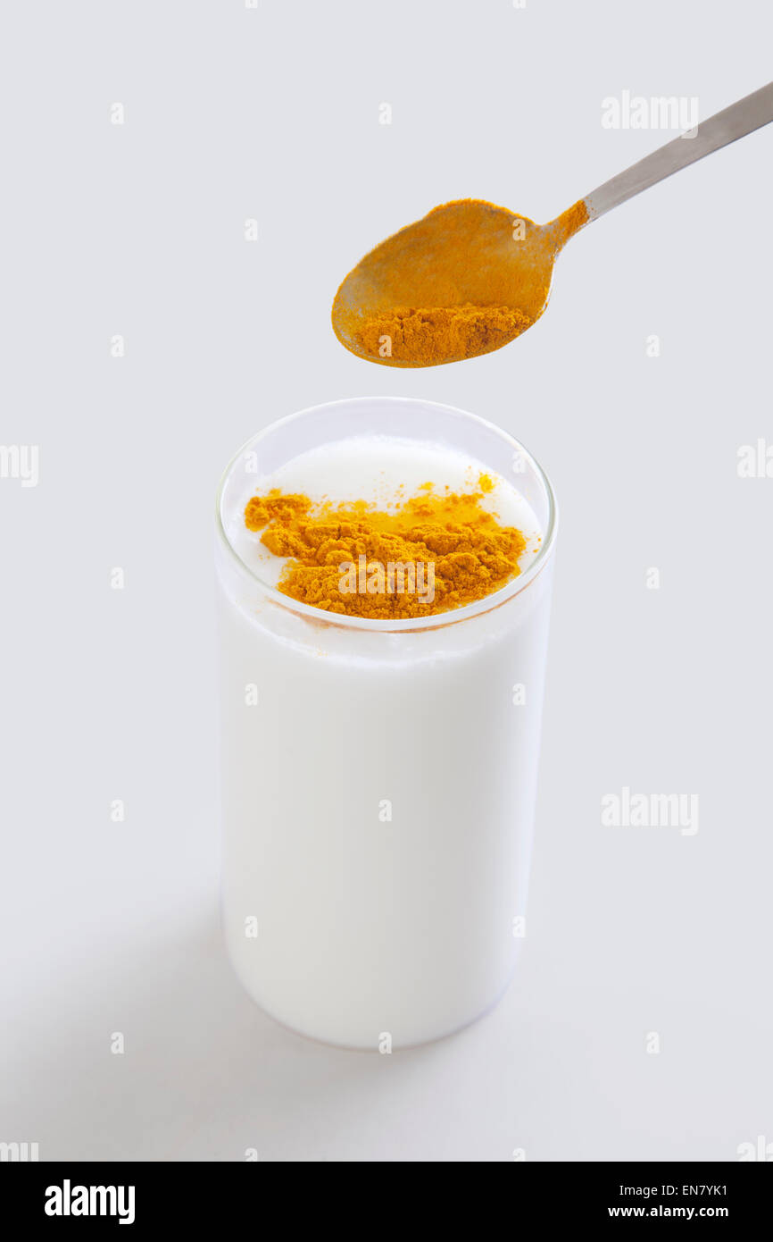 Kurkuma-Pulver in Glas Milch gießen Stockfoto
