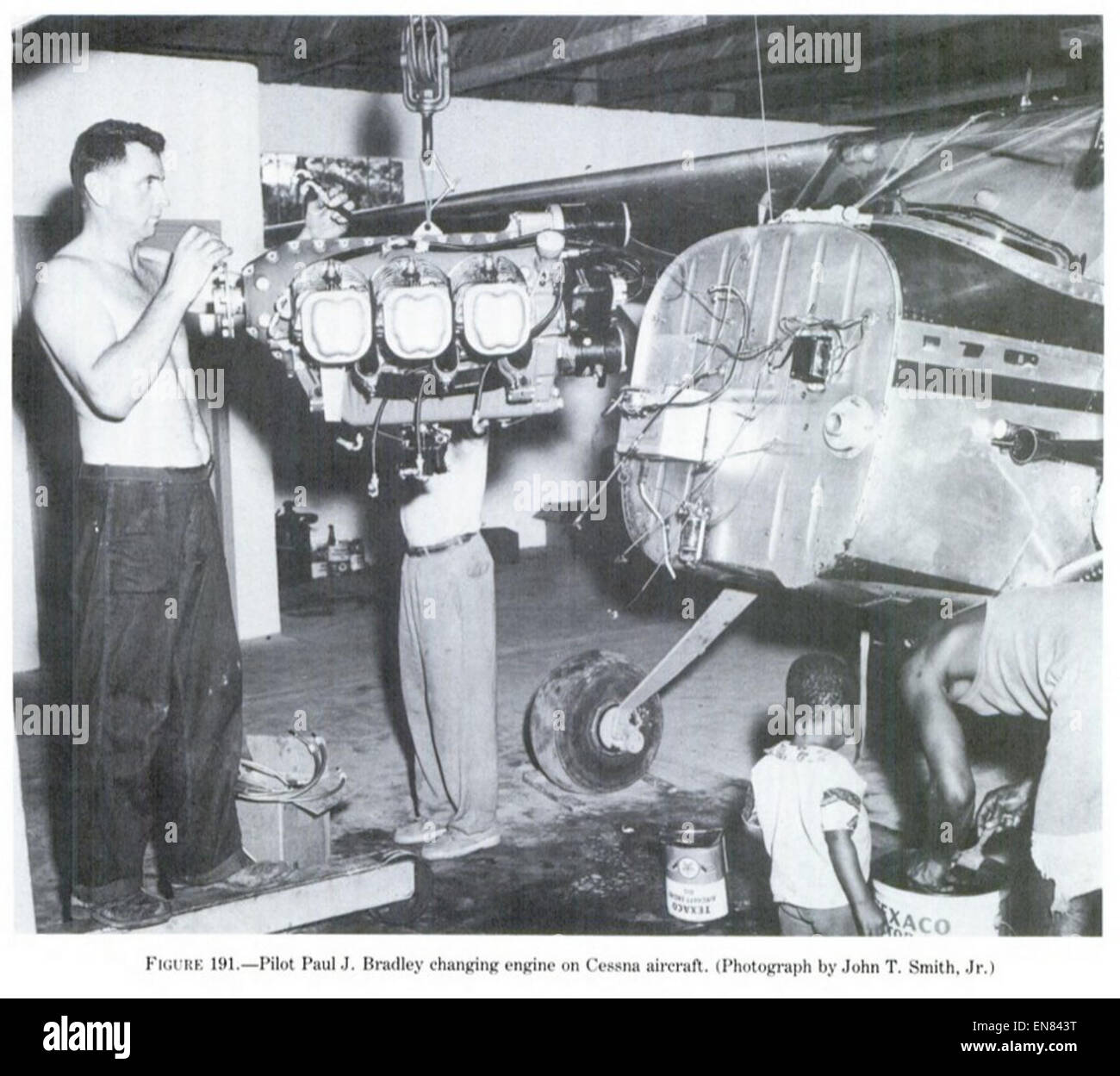 Dieses Bild aus dem Jahr 1955 zeigt den Piloten Paul J. Bradley, der einen Triebwerkwechsel an einem Cessna-Flugzeug durchführt und die Wartungs- und Betriebsaspekte der Luftfahrt während dieser Zeit widerspiegelt. Stockfoto
