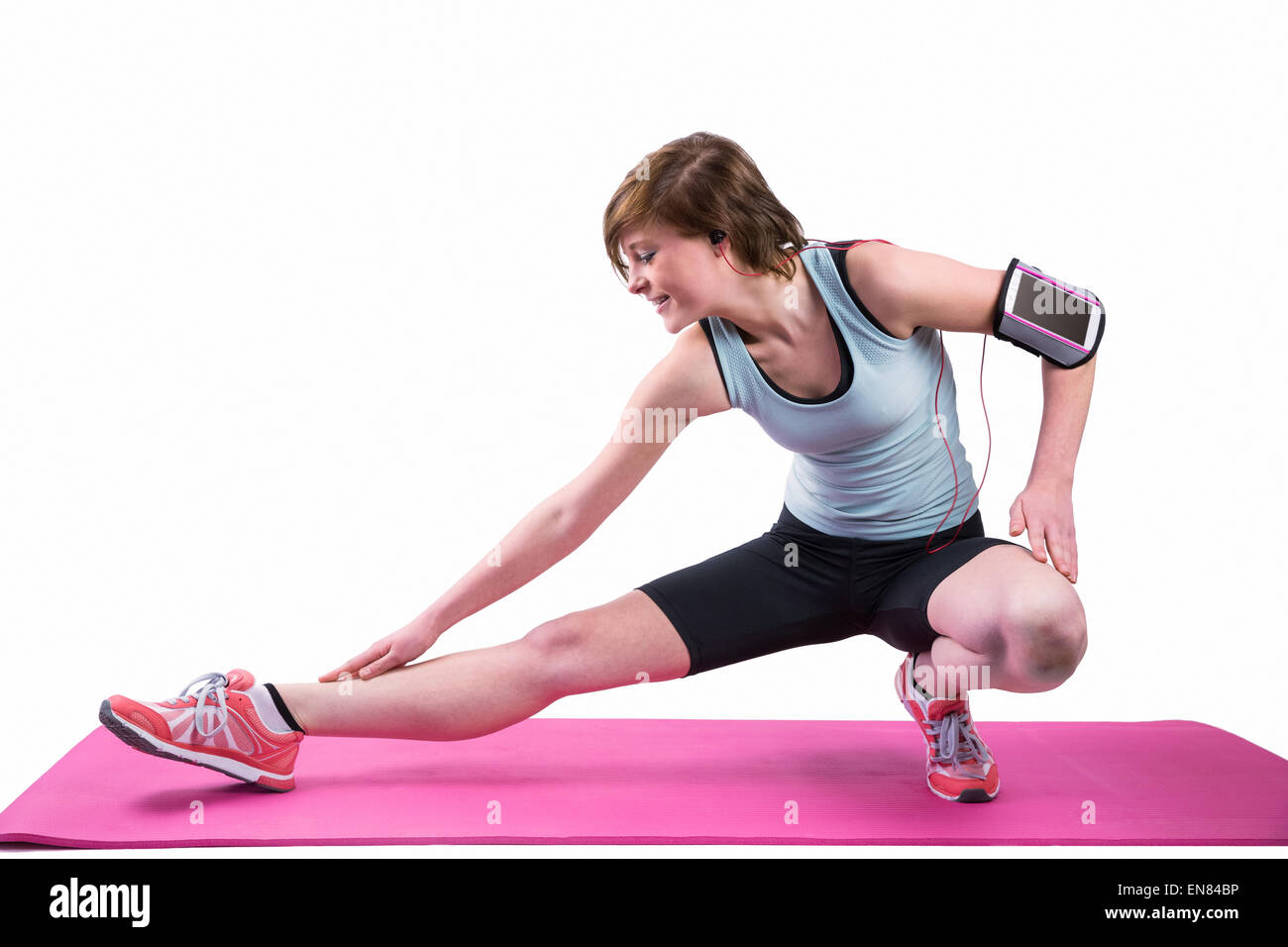 Hübsche Brünette stretching ihr Bein auf Gymnastikmatte Stockfoto