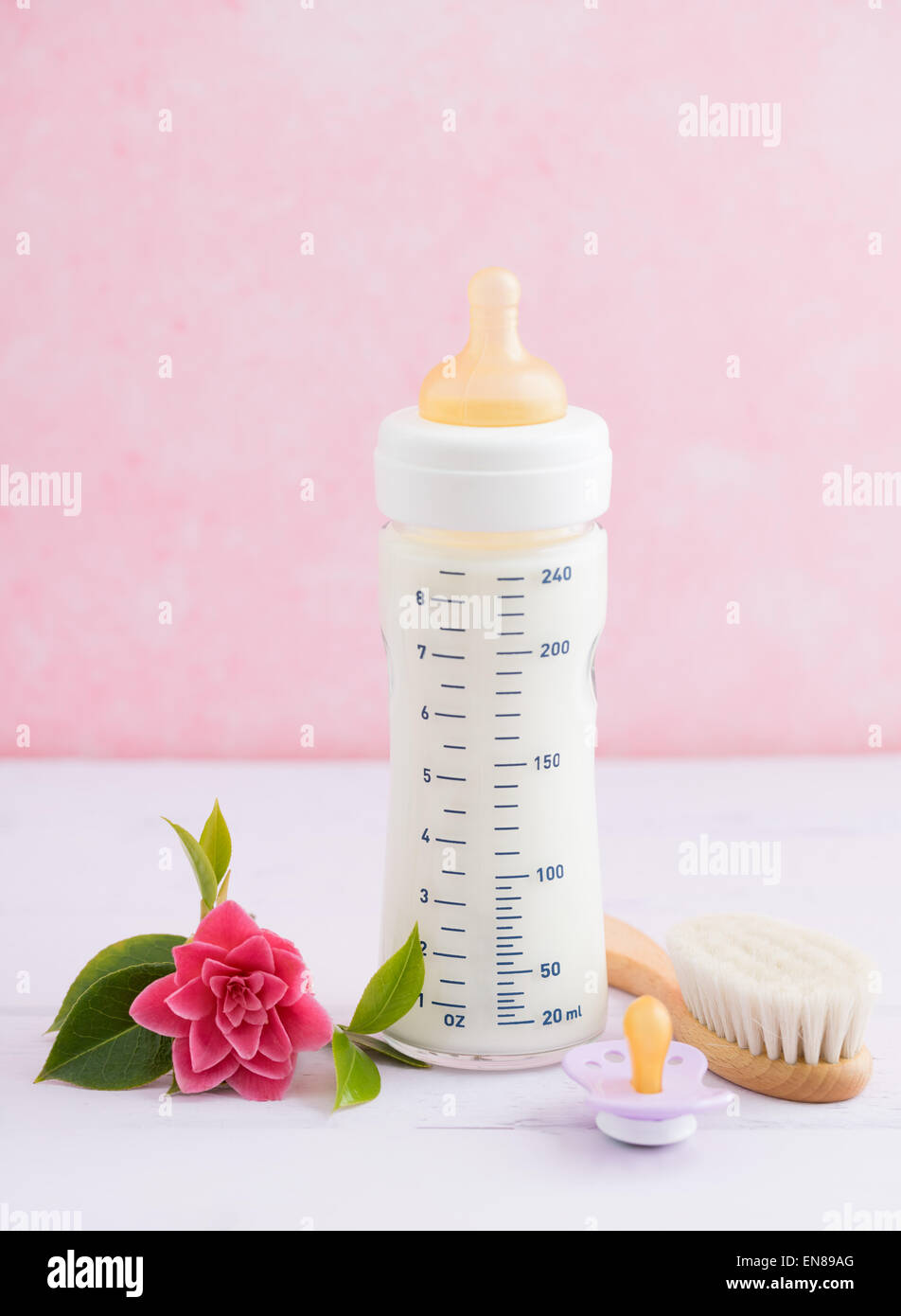 Babyflasche, Schnuller und Haarbürste auf rosa Tisch Stockfoto