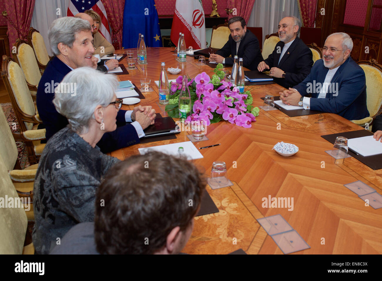 US-Außenminister John Kerry - flankiert von Under Secretary Of State für politische Angelegenheiten Wendy Sherman, US Energie-Staatssekretär Dr. Ernest Moniz, National Security Council Senior Director für den Iran, Irak, Syrien und den Golfstaaten Robert Malley und stellvertretende Generalsekretär der Europäischen Union Helga Schmid - sitzt gegenüber dem iranischen Außenminister Javad Zarif, Dr. Ali Akbar Salehi, der Vizepräsident des Iran für Atomenergie und Präsident der Atomic Energy Organization of Iran , und anderen Beratern am 28. März 2015, in Lausanne, Schweiz, vor der Wiederaufnahme der Verhandlungen über die Zukunft der Stockfoto