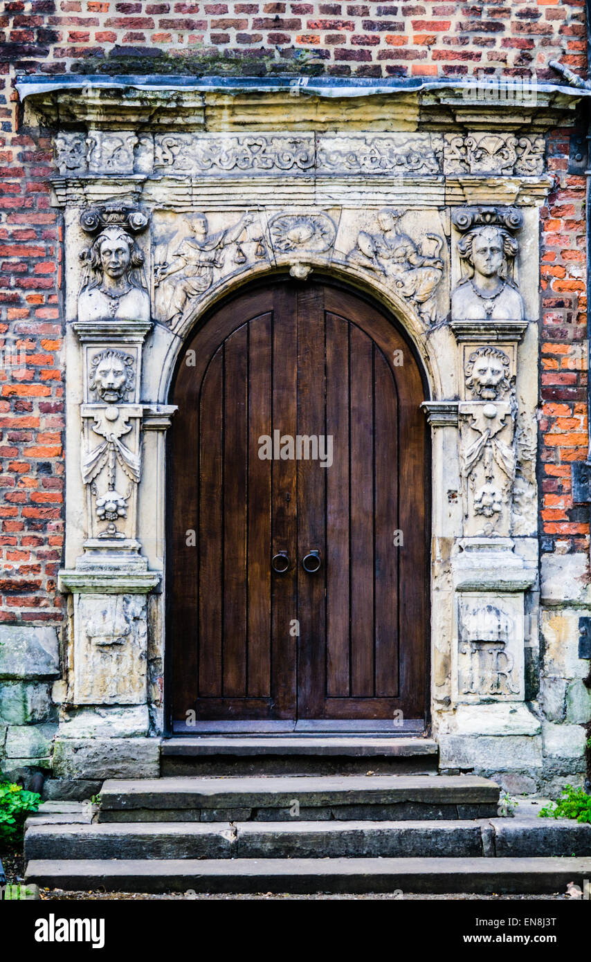 Mittelalterliche rundbogige Tür, dunklen hölzernen Doppeltüren, aufwendige verschönert Surround, King es Manor, York, UK Stockfoto