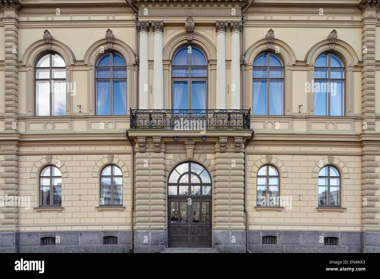 Alte klassische Fassade mit Fenstern, Balkon und sehr schöne Tür. Blauer Himmel Reflexionen in den Fenstern. Stockfoto