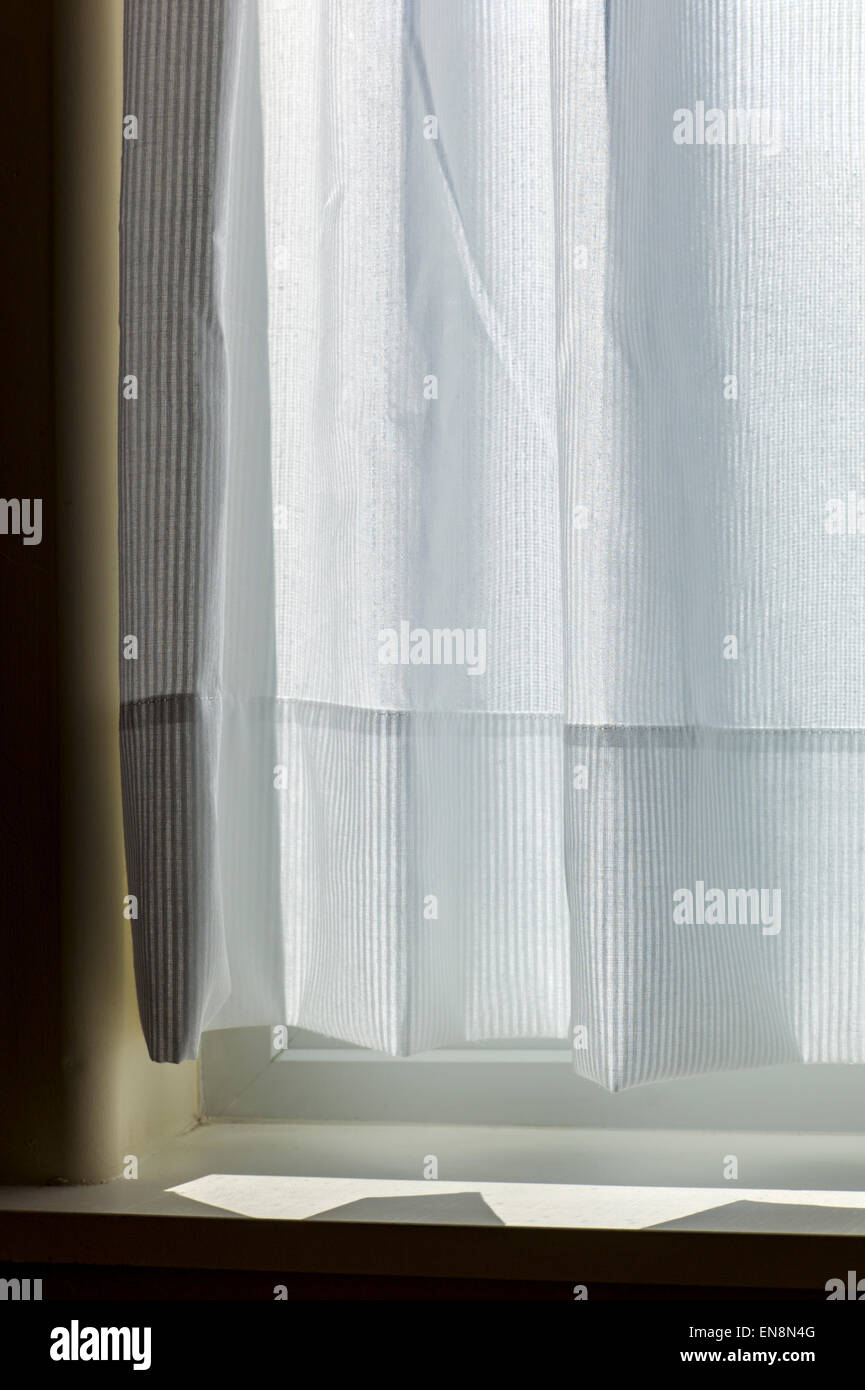 Sonnenlicht schafft abstrakte Muster auf eine zarte weiße Baumwolle Fenstervorhang Stockfoto