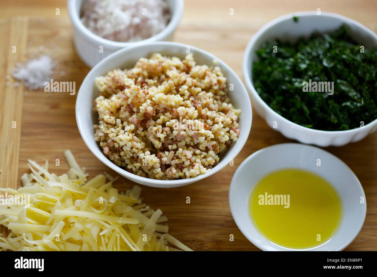 Schalen mit vorbereiteten Zutaten einschließlich gekochte Quinoa, gehackten Grünkohl, Zwiebeln, geriebenem Käse, Olivenöl & eine Prise Salz. Stockfoto