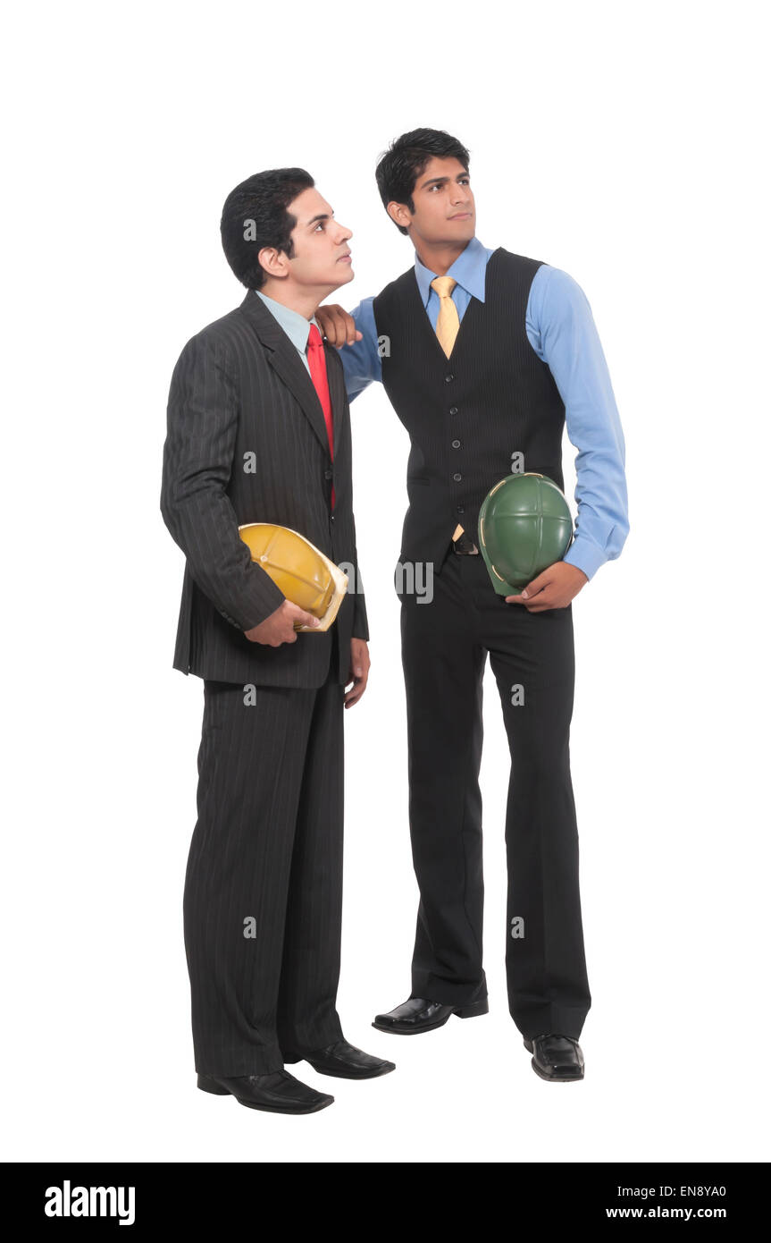 Zwei asiatische professionelle Männer stehen, gemeinsam mit Helmen in ihren Händen Stockfoto