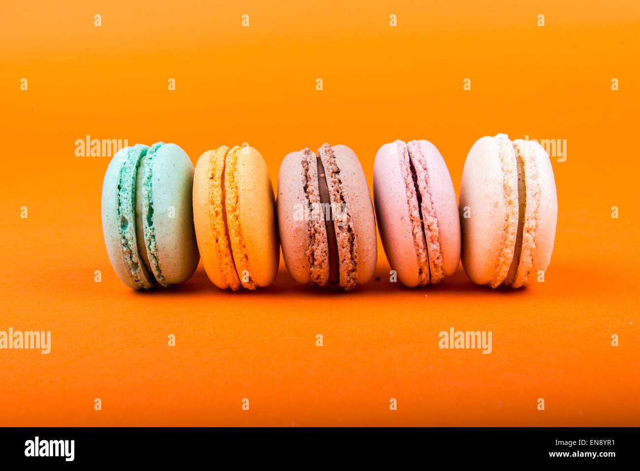 Satz von Macarons auf orangem Hintergrund isoliert Stockfoto