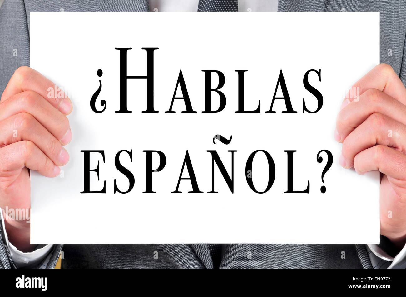ein Mann in einem Anzug hält ein Schild mit dem Satz Hablas Espanol? Sprichst du Spanisch? geschrieben in Spanisch Stockfoto