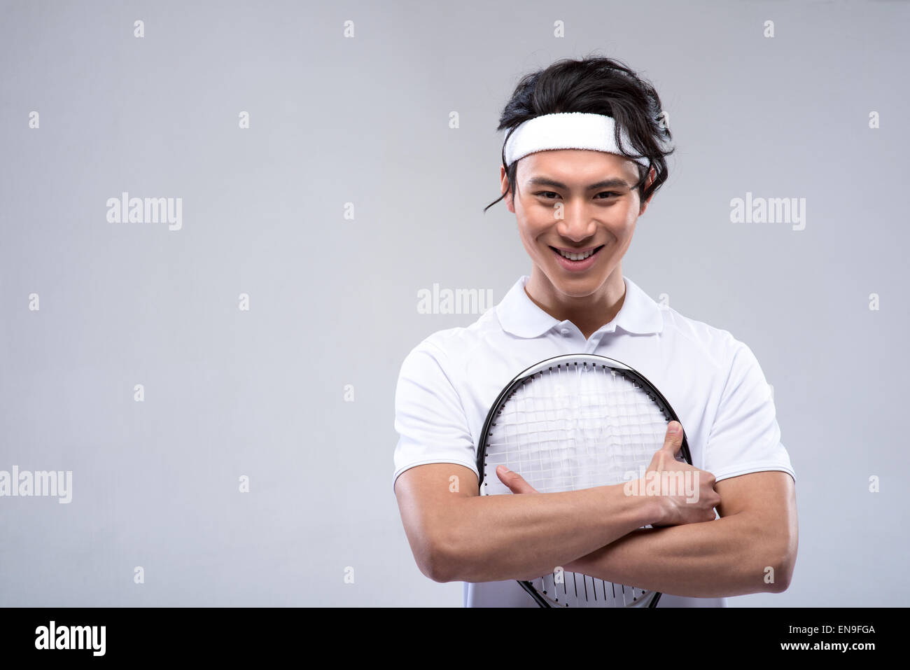 Junger Mann umarmt Tennisschläger Stockfoto