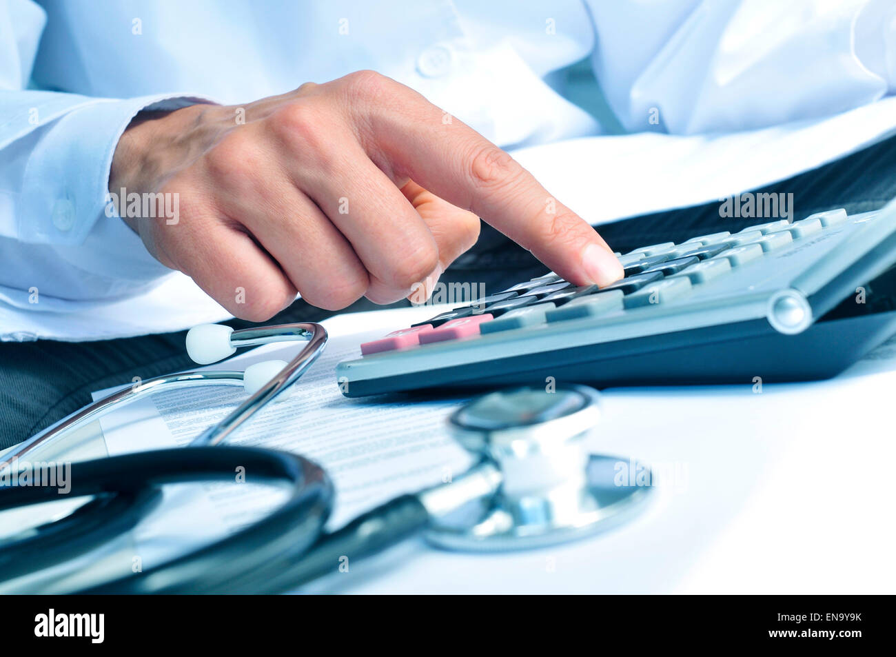 Nahaufnahme des jungen kaukasischen medizinisches Fachpersonal trägt einen weißen Mantel berechnet auf einer elektronischen Taschenrechner Stockfoto