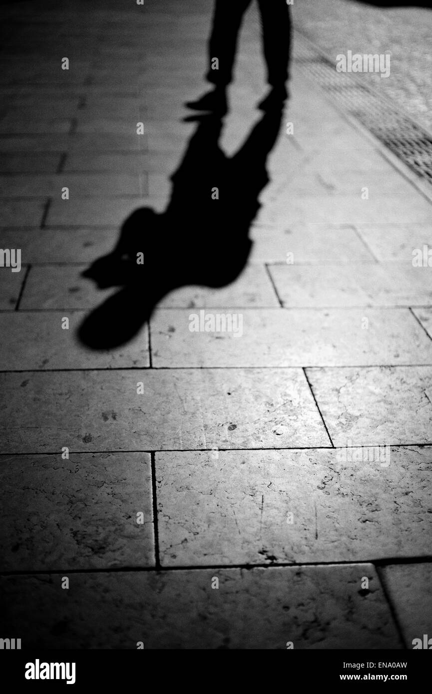 Dunkle Schatten einer menschlichen Figur in einer Straße in B&W. Stockfoto