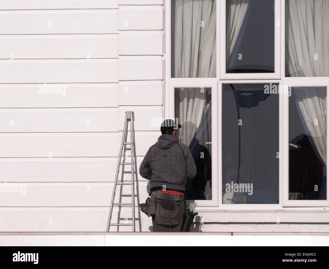 Ein Fensterputzer starrt aus dem Fenster eines Hauses Stockfoto