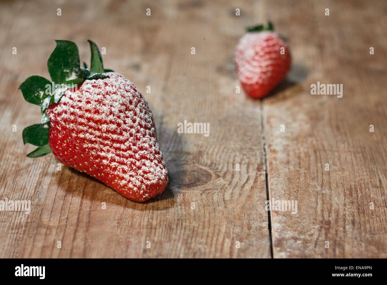 Rote Erdbeeren mit Zucker auf einem Holztisch bestreut Stockfoto