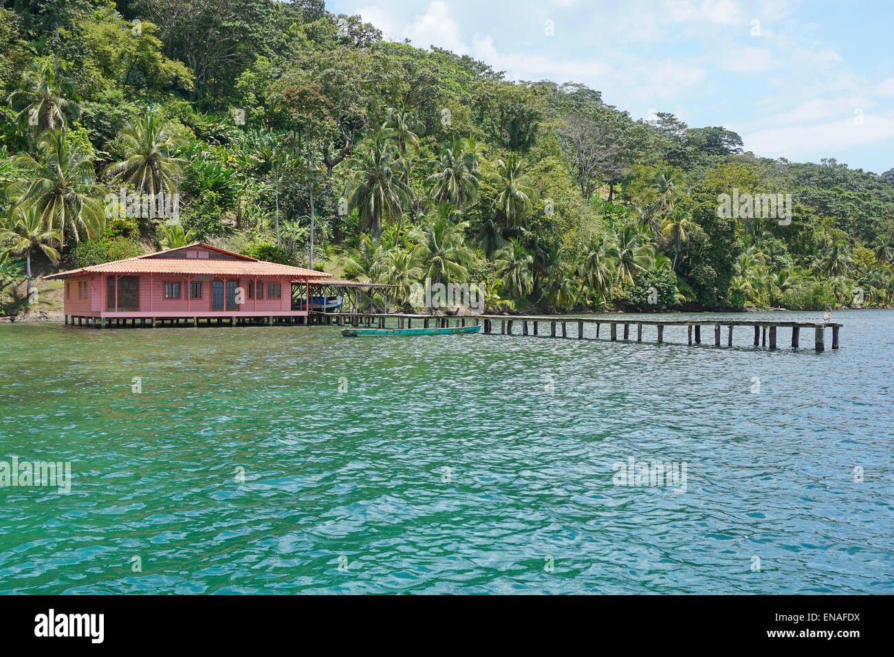 Tropenhaus mit dock über das Meer und einer üppigen tropischen Vegetation auf dem Lande, Karibik Küste von Panama, Bocas del Toro Stockfoto