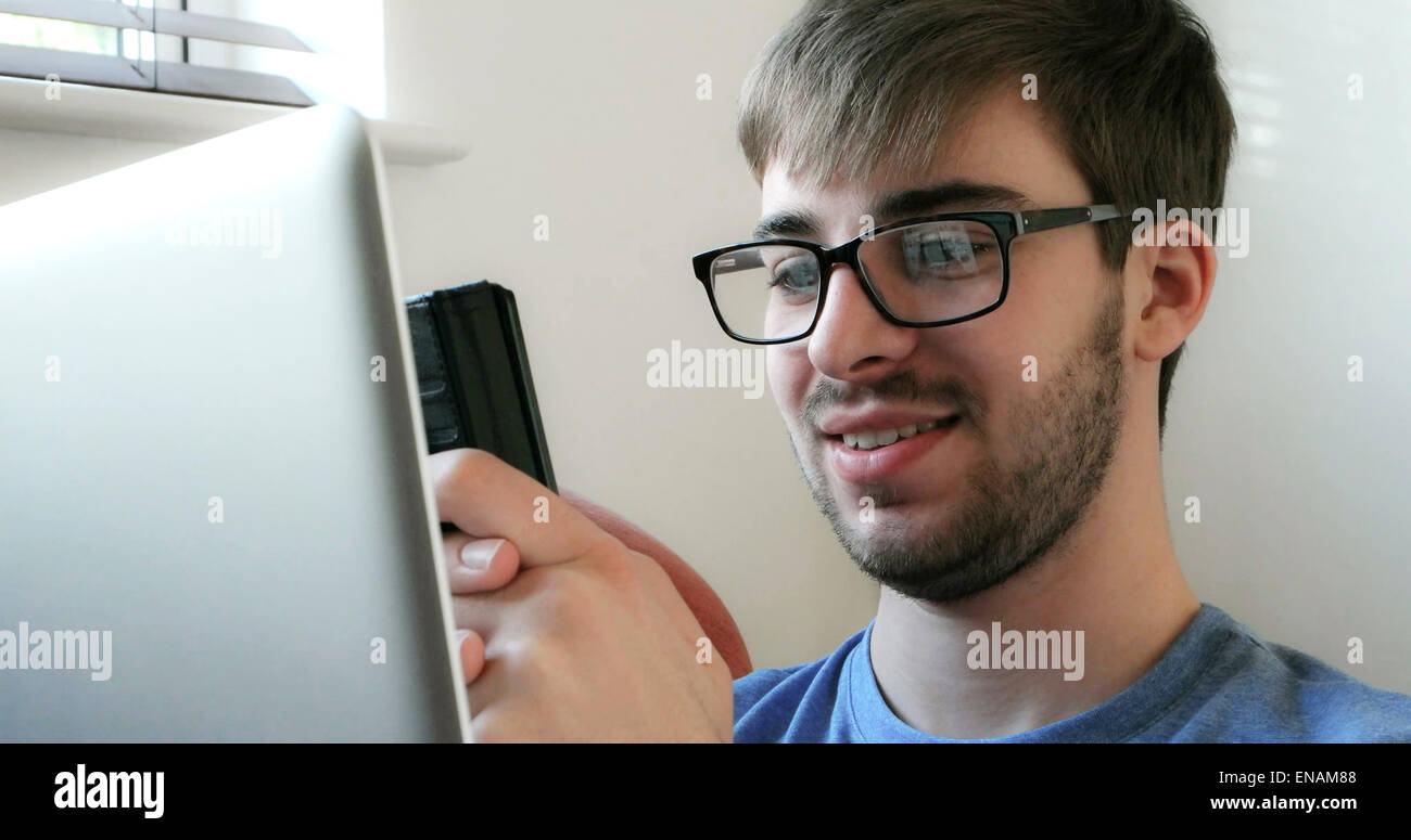 Junger Mann mit Handy und Laptop. Stockfoto