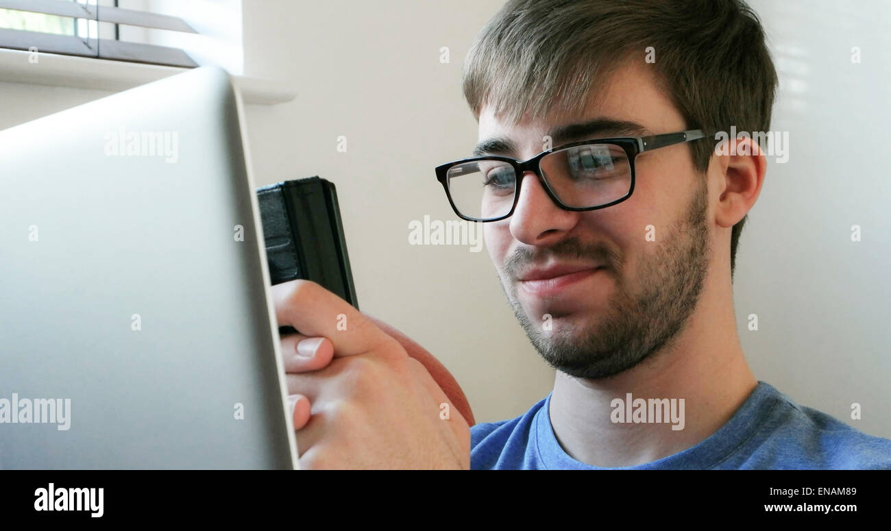 Junger Mann mit Handy und Laptop. Stockfoto