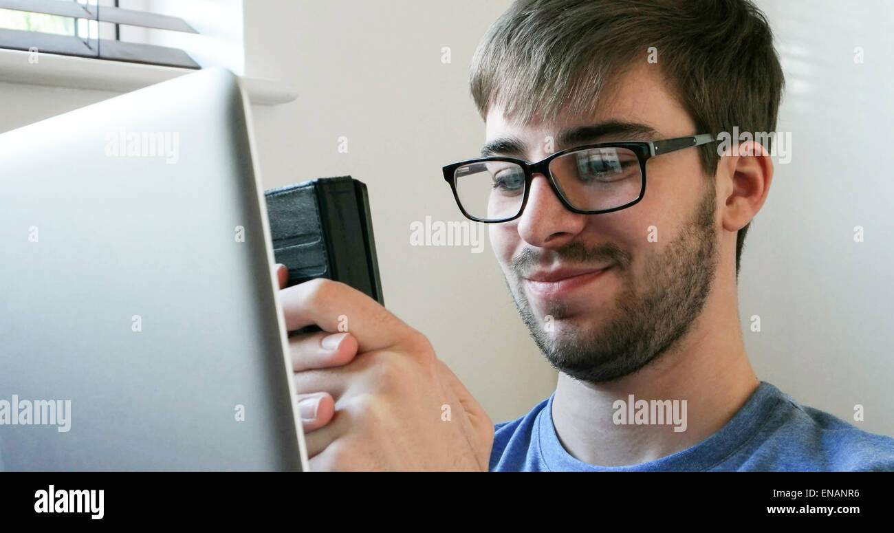 Junger Mann mit Handy und Laptop. Stockfoto