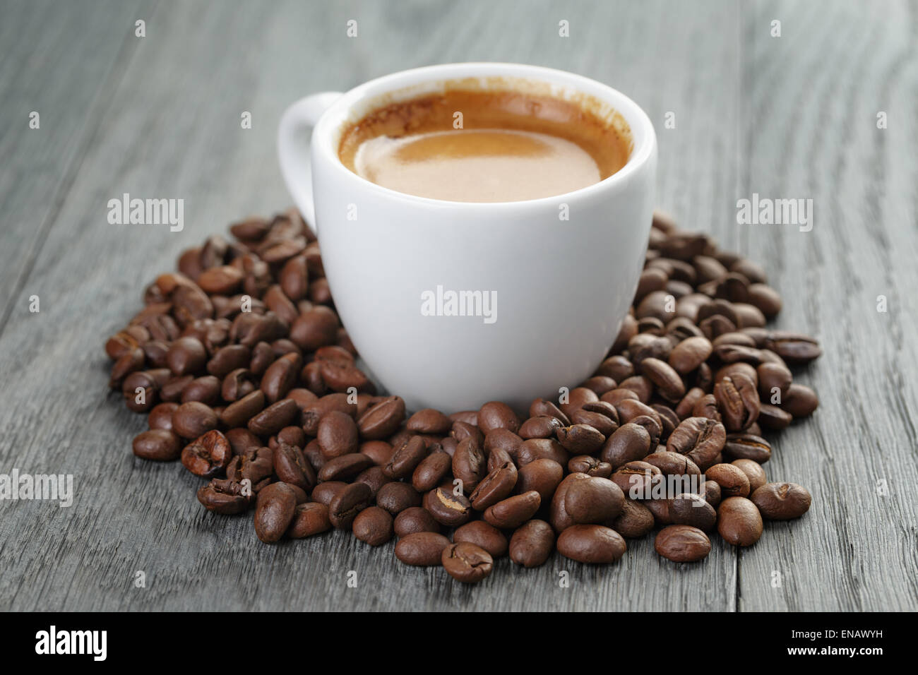 Tasse frischen Espresso mit Kaffeebohnen auf Eichentisch Stockfoto