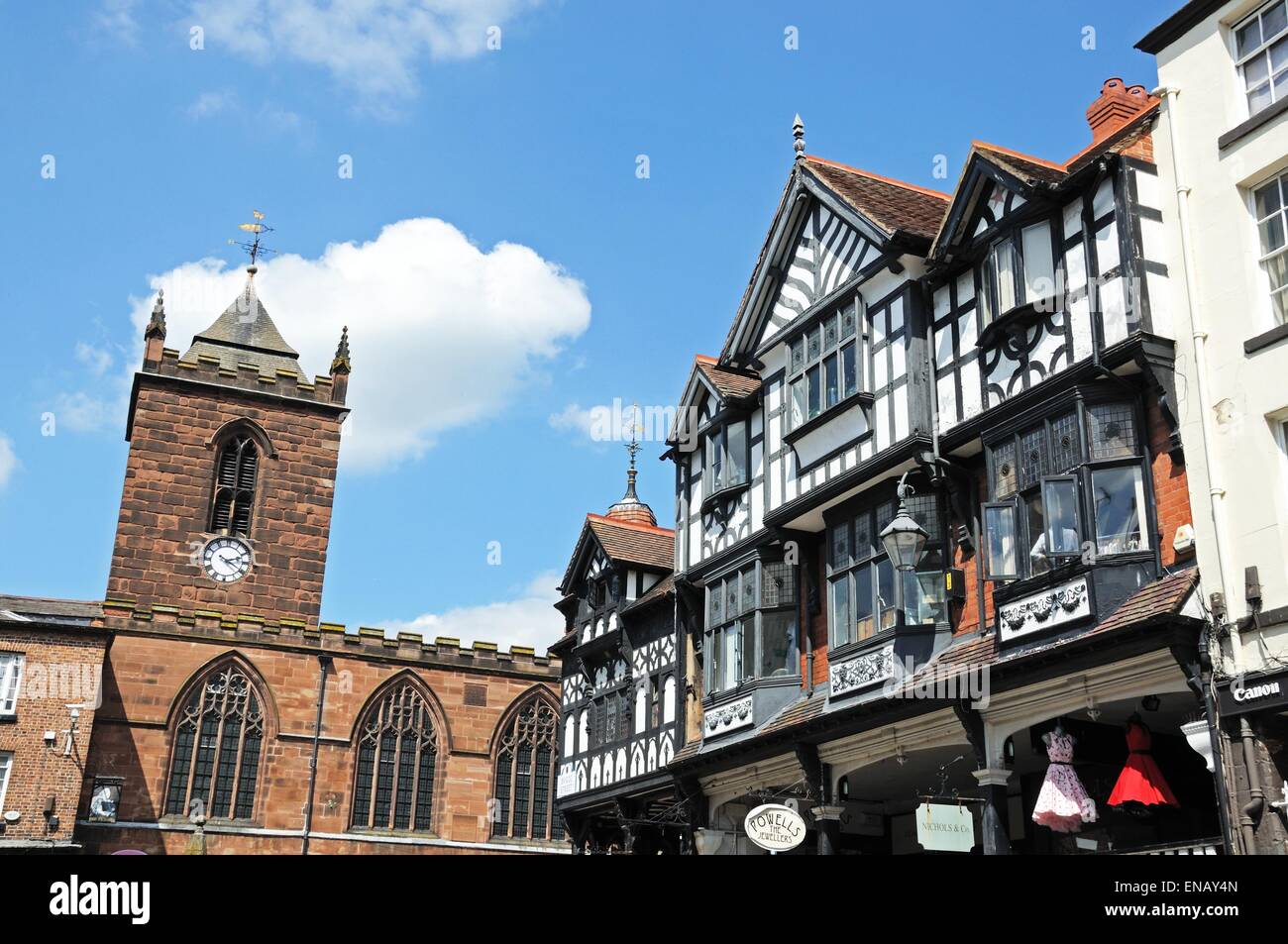 Gebäude und Geschäfte entlang der Bridge Street an der Ecke der Eastgate Street mit St. Peterskirche an der Rückseite, Chester, England. Stockfoto