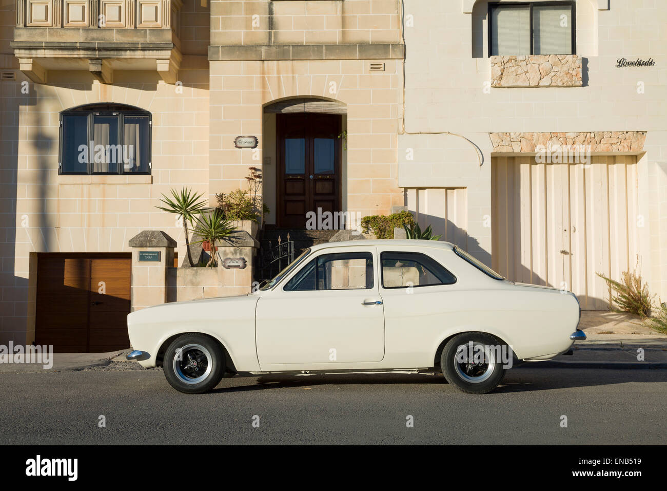 Ford Escort MKI Malta in weiß mit Häusern im Hintergrund. Stockfoto