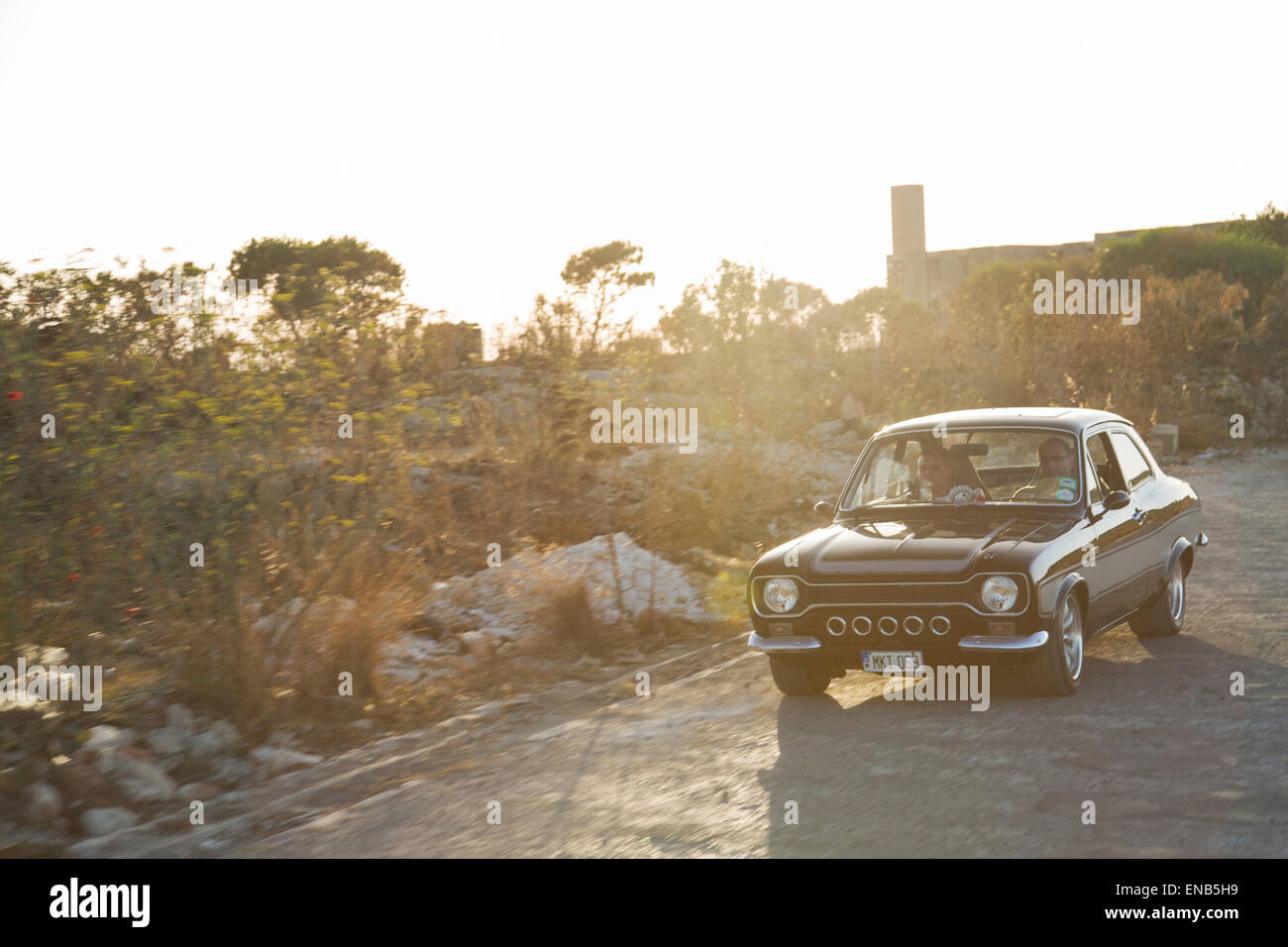 Ford MKI Escort in Malta, schwarzen Auto in Bewegung mit einem natürlichen Sonne Aufflackern Stockfoto