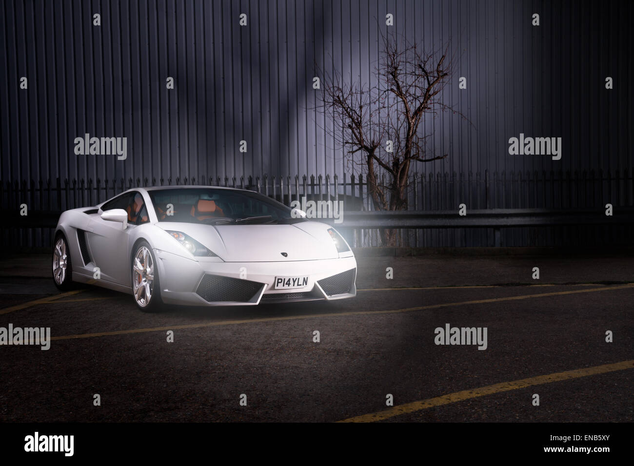 Lamborghini Gallardo in weiß setzte gegen industriellem Hintergrund. Vorderen 3/4 mit Scheinwerfern. Stockfoto
