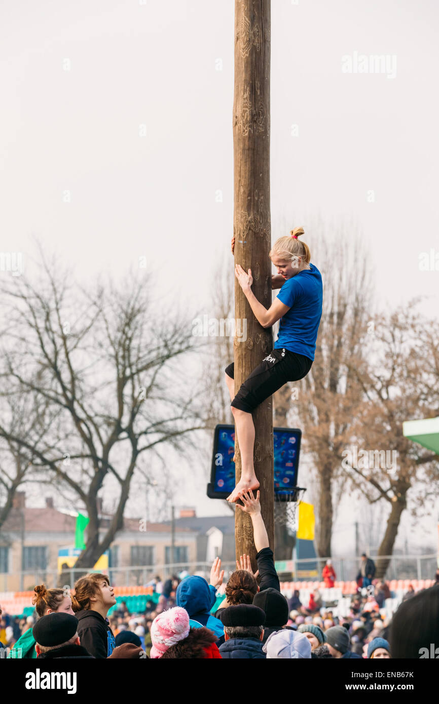 Junge Frau klettert auf Holzpfosten im traditionellen Urlaub Ansatz des Frühlings - slawischen feiern Fasching gewidmet. Stockfoto