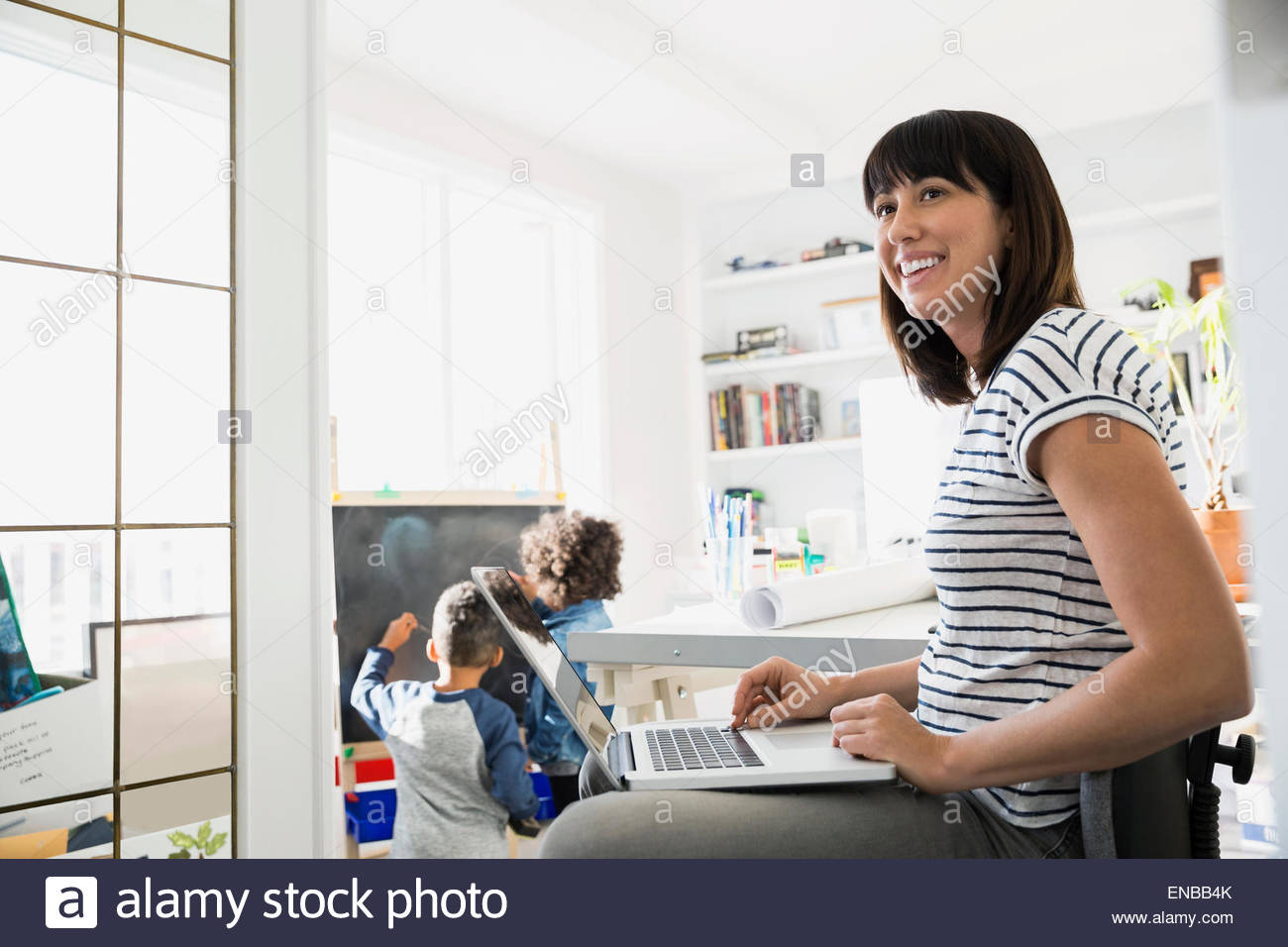 Mutter mit Kindern im Hintergrund am Laptop arbeiten Stockfoto