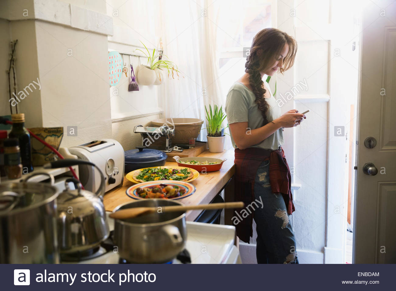 Frau SMS mit Handy in Küche kochen Stockfoto