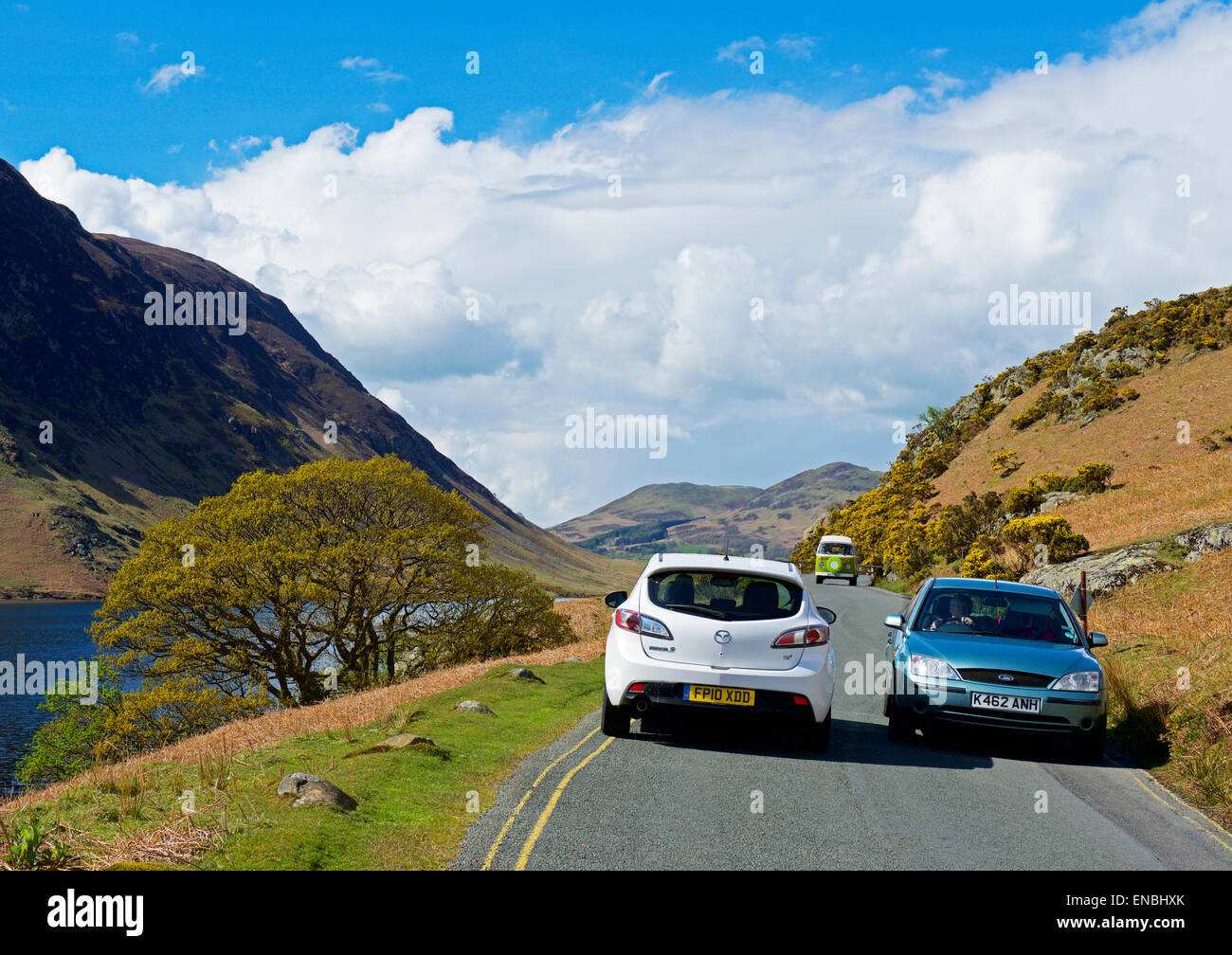 Autos fahren auf einer schmalen Straße neben Crummockwater (B5289), Lake District National Park, Cumbria, England Stockfoto