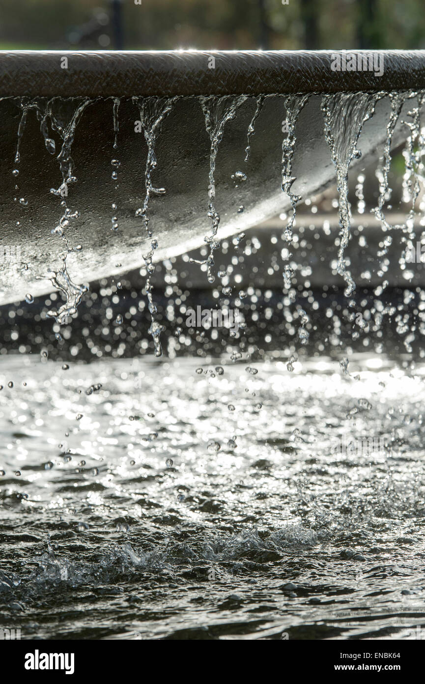 Überlaufende Wasser aus einem Gartenteich-Wasser-Funktion im Sonnenlicht bei RHS Wisley Gärten, Surrey, England Stockfoto