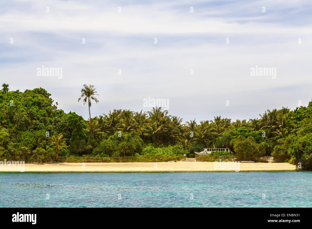 Grüne tropische Insel mit Palmen auf gelben Felsstrand mit Steinen im blauen Meer, Philippinen Boracay island Stockfoto